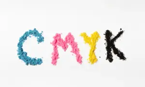 Litery CMYK uformowane z proszków: cyjan kolor, magenta, żółty i czarny.