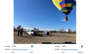 Kolorowy balon na gorące powietrze unosi się nad polem, gdzie stoją ludzie i samochody. Format HEIC zapewnia mniejszy rozmiar pliku.
