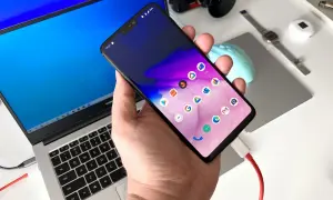 Podłączanie telefonu do laptopa, aby przesłać zdjęcia. Widoczny ekran telefonu z ikonami aplikacji i podłączony kabel USB.
