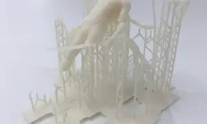 Biały, drukowany w 3D model postaci ludzkiej, przypominający fragment rzeźby lub projektu, osadzony na skomplikowanej, kratownicowej konstrukcji. Format pliku .fbx.