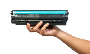 Dłoń trzymająca toner do drukarki HP. Dowiedz się, jak wymienić tusz w drukarce HP, aby drukować bez problemów.