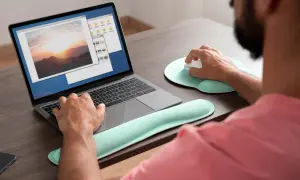 Mężczyzna pracuje na laptopie, przeglądając zdjęcia. Może szukać sposobu, **jak wyostrzyć zdjęcie**, aby poprawić jakość krajobrazu o zachodzie słońca.