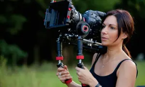 Kobieta trzymająca profesjonalną kamerę filmową na ramieniu.