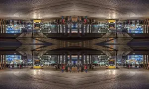 Nocne miasto z żółtym tramwajem i ludźmi. Kompozycja symetryczna tworzy surrealistyczny obraz.