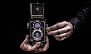 Dłonie trzymające aparat Rolleicord, uchwycone w kadrze zgodnym ze złotym podziałem.