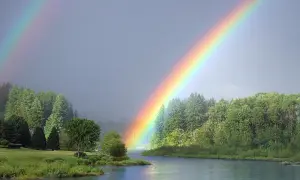 Piękna tęcza kolory nad jeziorem i lasem.