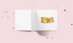 Otwarta biała kartka z fragmentem folii w kolorze **złota**.
