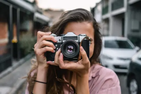 Dziewczyna z aparatem w rękach, idealna do kursu fotografii dla początkujących.