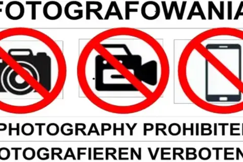 Tablica informuje o zakazie fotografowania. Widoczne są symbole aparatu, kamery i telefonu komórkowego przekreślone czerwoną linią.