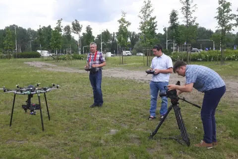 Trzech mężczyzn przygotowuje się do nagrywania filmów z drona i obsługi kamery na statywie.