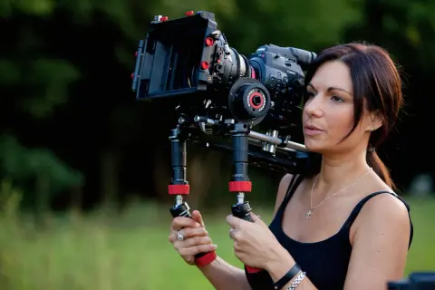 Kobieta trzymająca profesjonalną kamerę filmową na ramieniu.