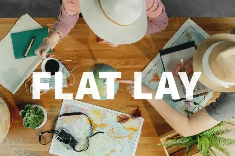 Widok z góry na stół z mapami, globusem, aparatem i notatkami. Dwie osoby planują podróż. To idealny **flat lay** do inspiracji.