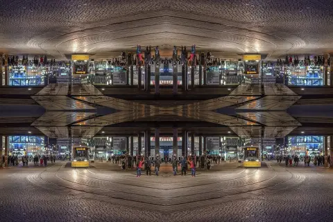 Nocne miasto z żółtym tramwajem i ludźmi. Kompozycja symetryczna tworzy surrealistyczny obraz.