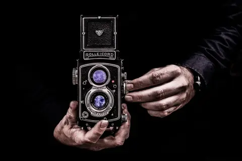 Dłonie trzymające aparat Rolleicord, uchwycone w kadrze zgodnym ze złotym podziałem.