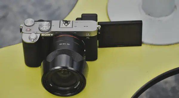 Aparat Sony a7c z obiektywem FE 1.8/35 na żółtym tle.