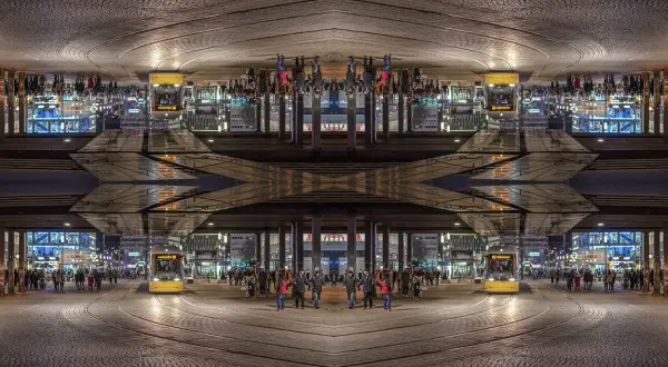 Nocne miasto z żółtym tramwajem i ludźmi. Kompozycja symetryczna tworzy surrealistyczny obraz.