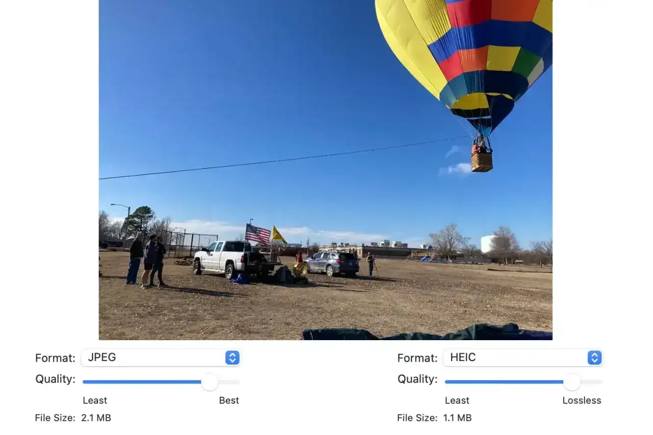 Kolorowy balon na gorące powietrze unosi się nad polem, gdzie stoją ludzie i samochody. Format HEIC zapewnia mniejszy rozmiar pliku.