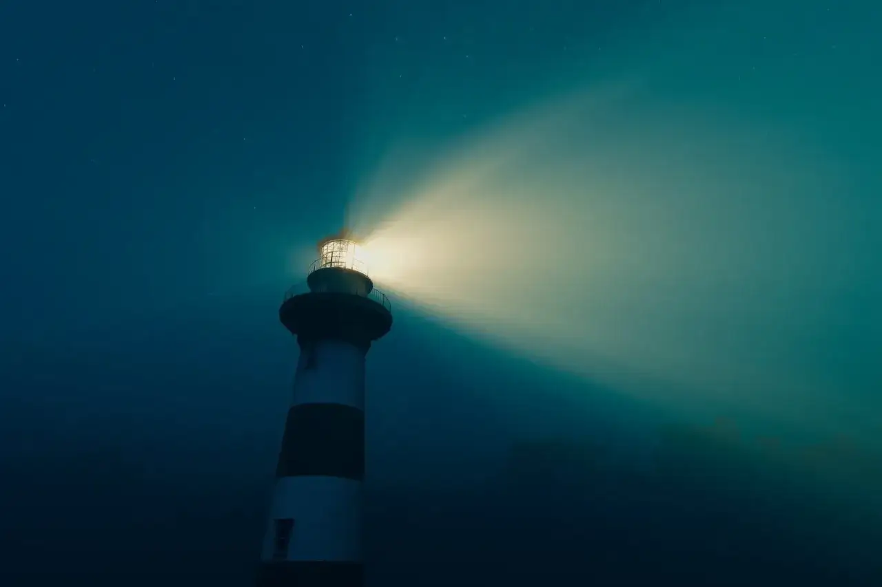 Latarnia morska z charakterystycznym światłem fresnel rozświetla nocne niebo, wskazując drogę.