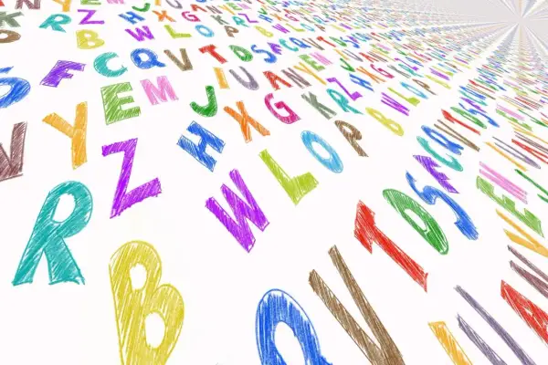 Kolorowe, kredowe litery tworzą wzór na białym tle. Widać wielką literę w druku, jak "R" i "B", a także inne znaki alfabetu.
