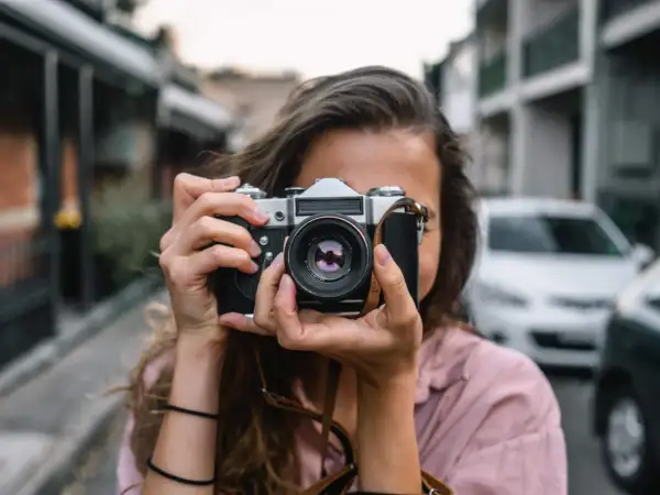 Dziewczyna z aparatem w rękach, idealna do kursu fotografii dla początkujących.