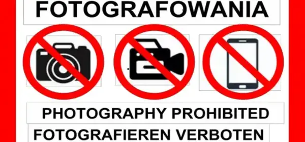 Tablica informuje o zakazie fotografowania. Widoczne są symbole aparatu, kamery i telefonu komórkowego przekreślone czerwoną linią.