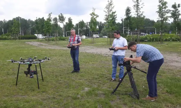 Trzech mężczyzn przygotowuje się do nagrywania filmów z drona i obsługi kamery na statywie.