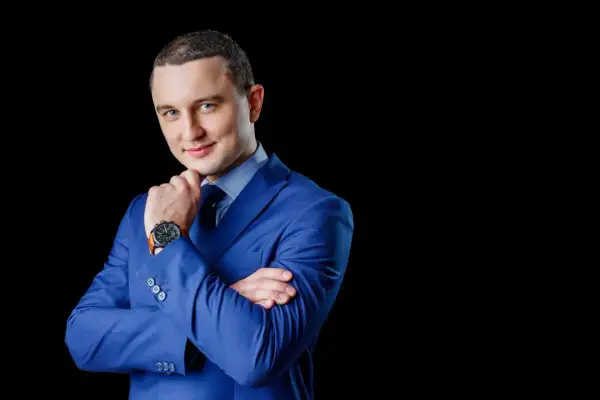 Elegancki mężczyzna w niebieskiej marynarce, z dłonią na podbródku. Profesjonalne zdjęcie do CV.