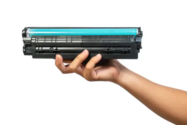 Dłoń trzymająca toner do drukarki HP. Dowiedz się, jak wymienić tusz w drukarce HP, aby drukować bez problemów.