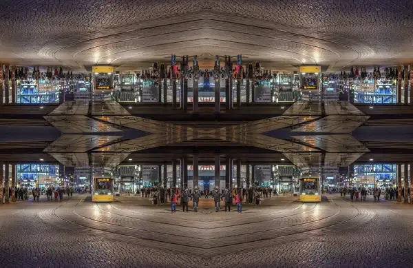 Nocne miasto z żółtym tramwajem i ludźmi. Kompozycja symetryczna tworzy surrealistyczny obraz.