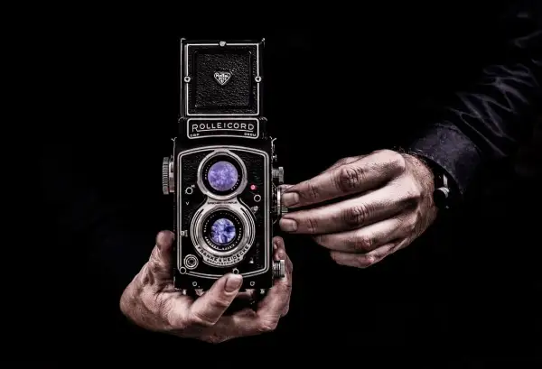 Dłonie trzymające aparat Rolleicord, uchwycone w kadrze zgodnym ze złotym podziałem.